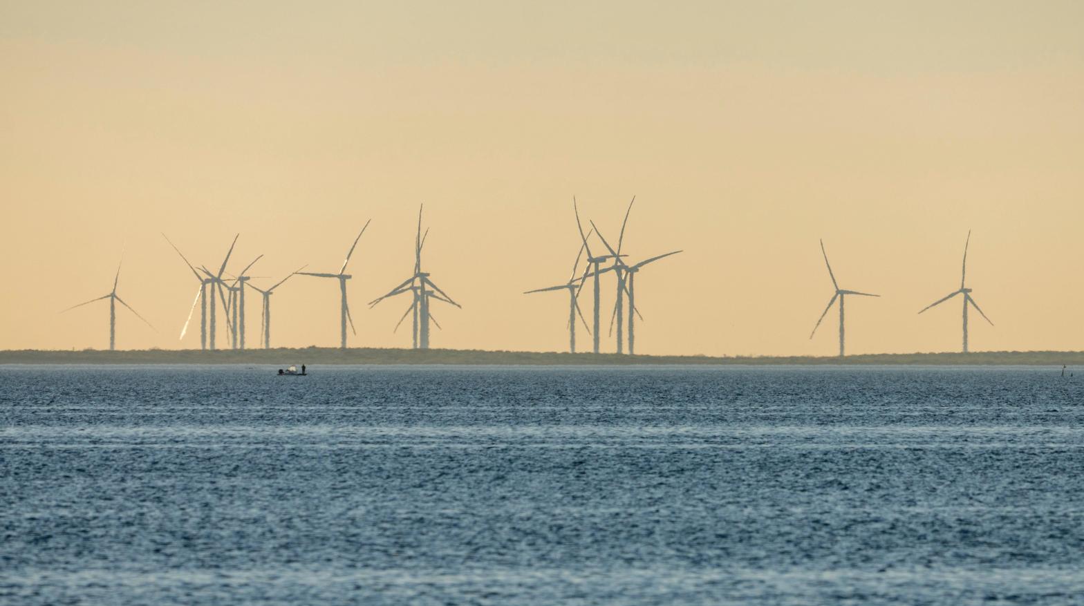 Fishermen in a boat on the Laguna Madre in front of giant wind generators on the mainland near Port Isabel, Texas. (Photo: Jon G. Fuller / VWPics, AP)