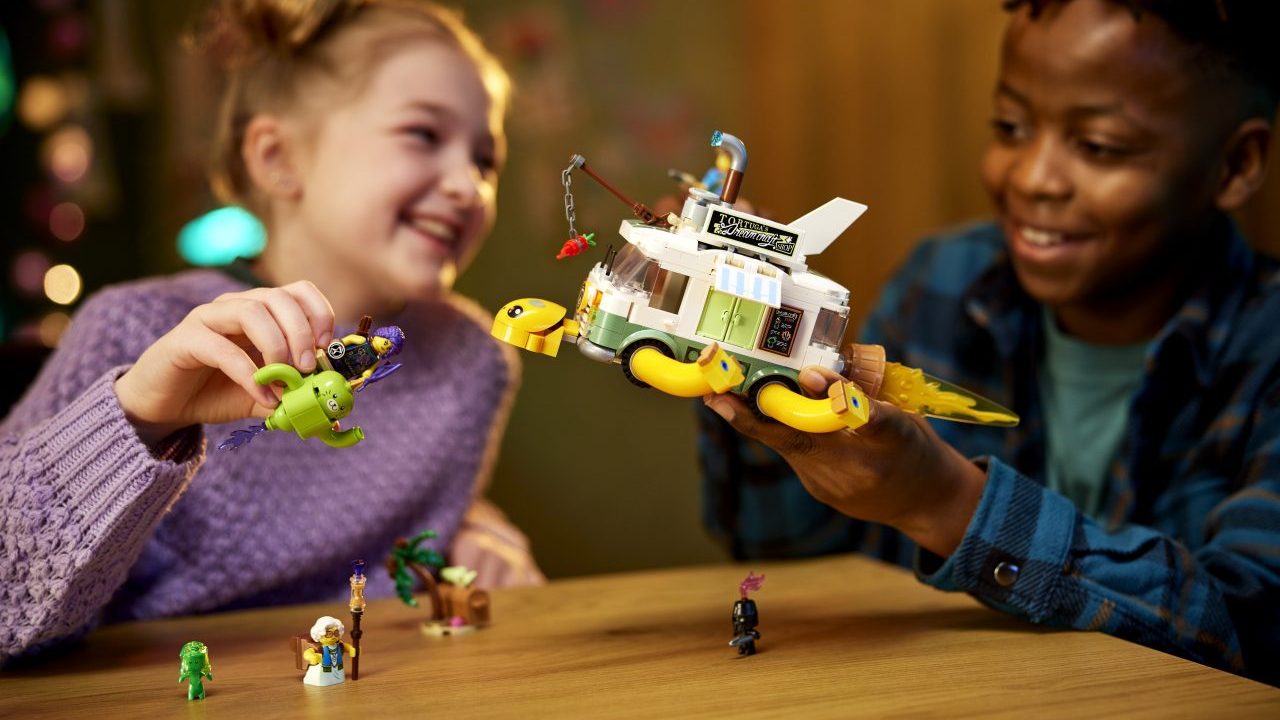 Two kids playing with a Lego Dreamzzz set that looks like a cross between a space ship and a school bus