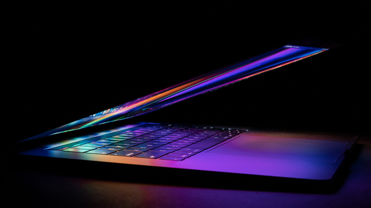 a laptop half closed bright and glowing in a dark background.