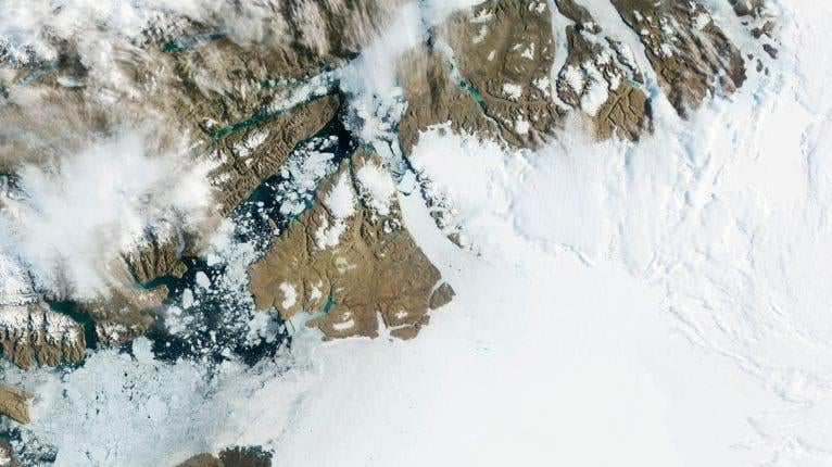 Petermann Glacier in northwest Greenland gradually moves toward the ocean, with large segments breaking off and drifting away as icebergs. (Photo: NASA, Fair Use)