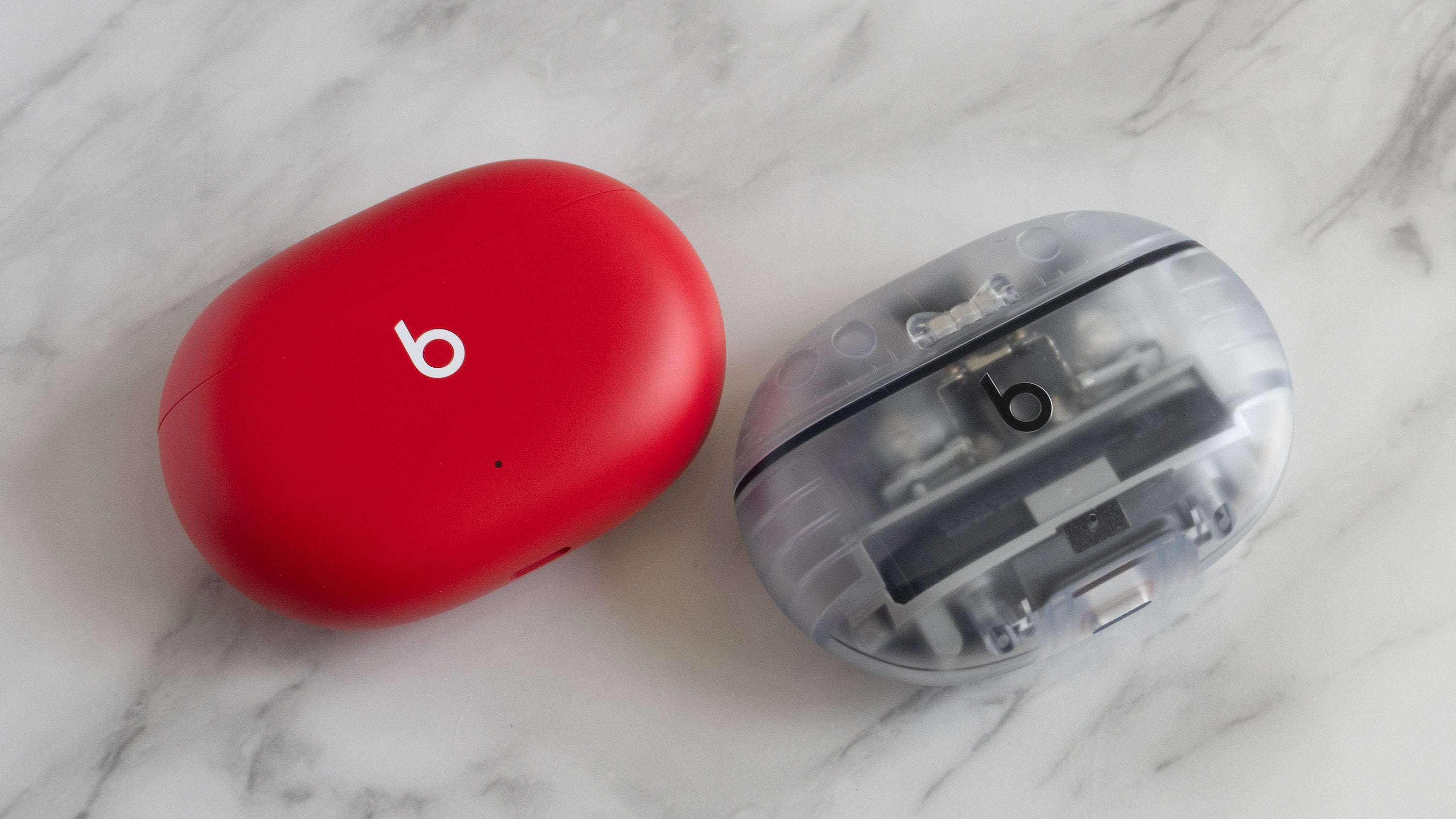 Aside from the new transparent colorway for the Beats Studio Buds + (right), the charging case is almost impossible to distinguish from the previous version (left). (Photo: Andrew Liszewski | Gizmodo)