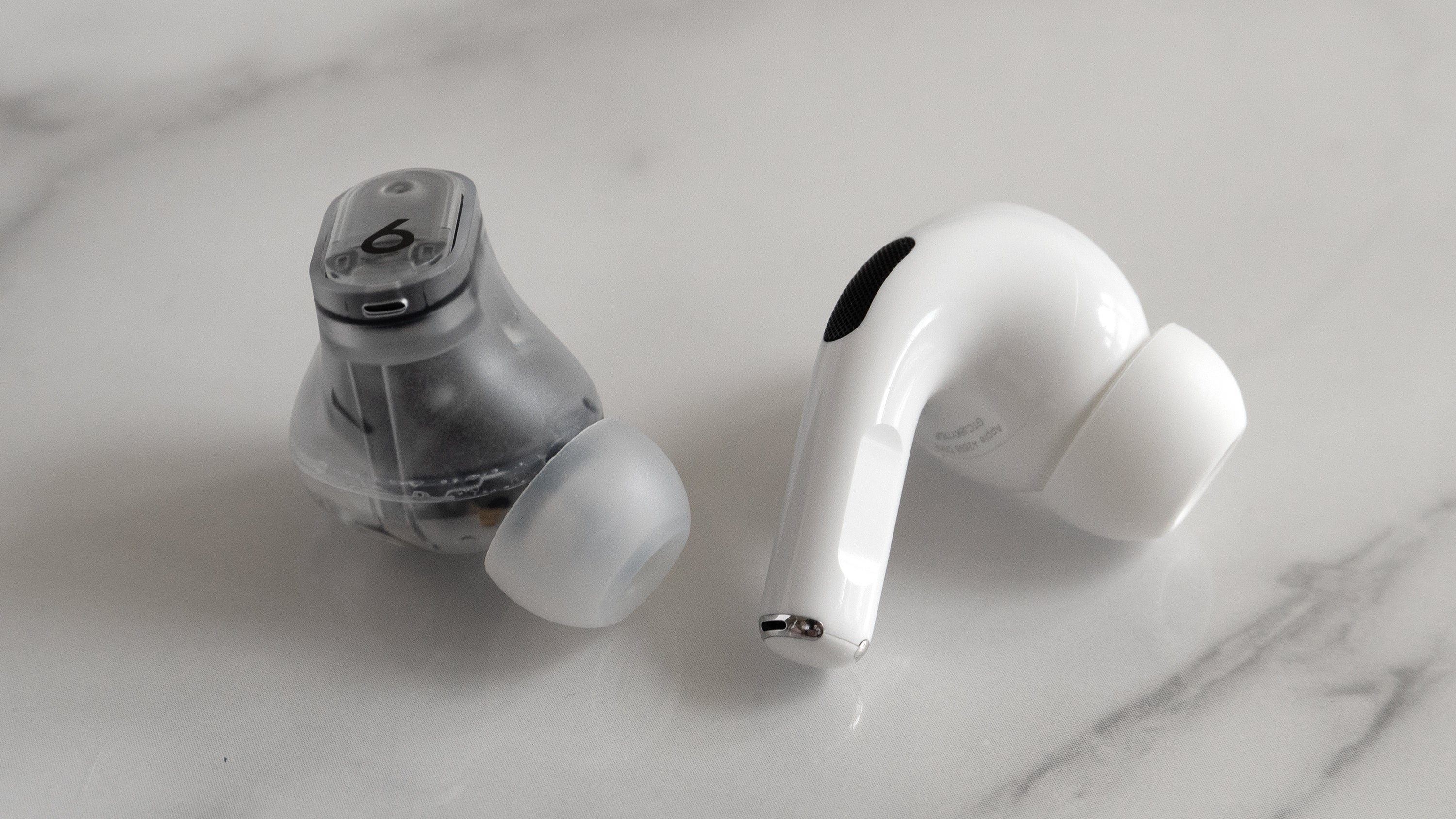 The Beats Studio Buds + (left) feature a more traditional in-ear earbud design, compared to the Apple AirPods Pro 2 (right) which house some of the electronics in a protruding stem. (Photo: Andrew Liszewski | Gizmodo)