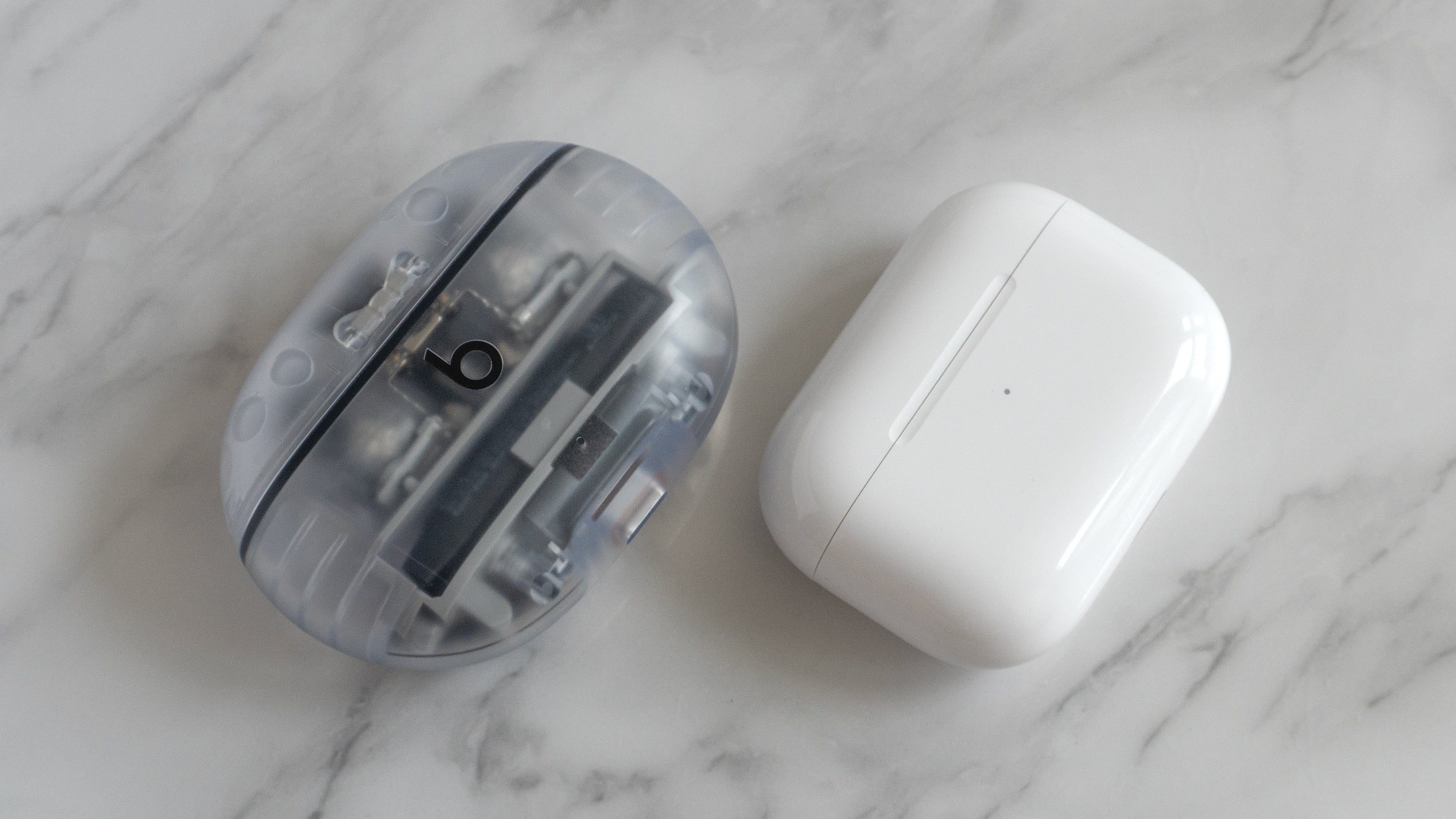 The Beats Studio Buds + charging case (left) is a bit chunkier than the AirPods Pro 2 charging case (right). (Photo: Andrew Liszewski | Gizmodo)