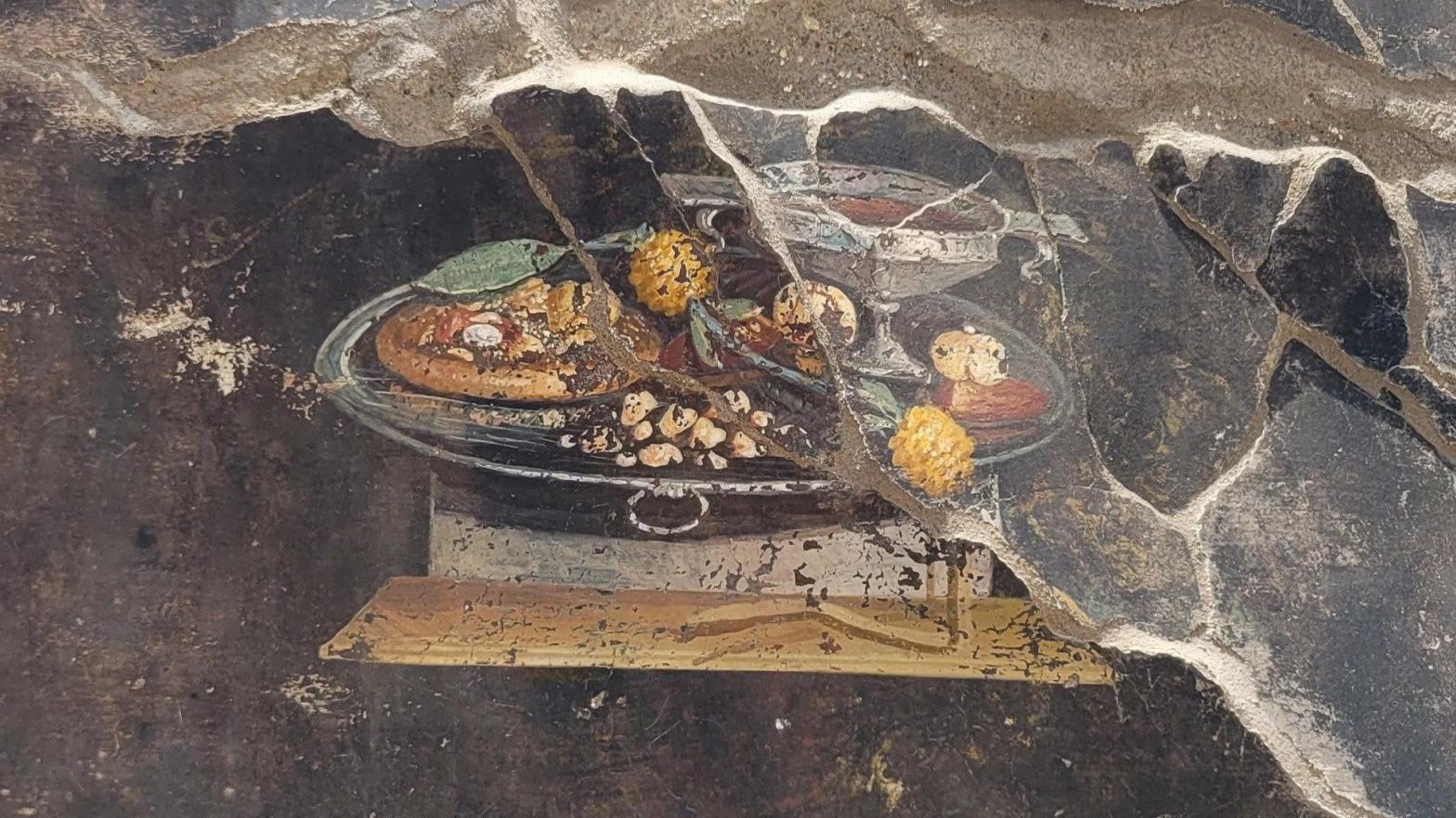 The still life fresco of a food platter, with mensa flatbread at left. (Photo: Archaeological Park of Pompeii / Italian Ministry of Culture)