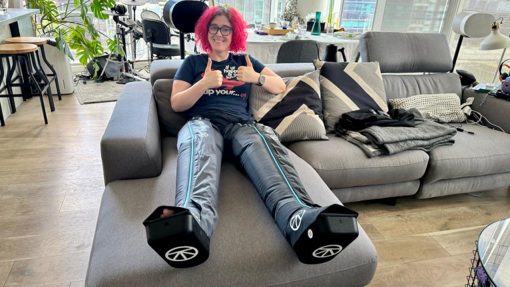 Alice wearing Therabody RecoveryAir Jetboots on a couch.