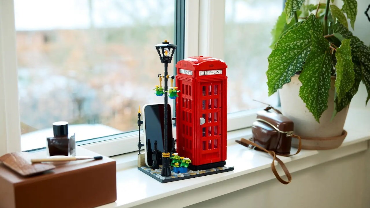 Lego London Telephone Box sitting on a windowsill holding a phone, for some unknown reason.